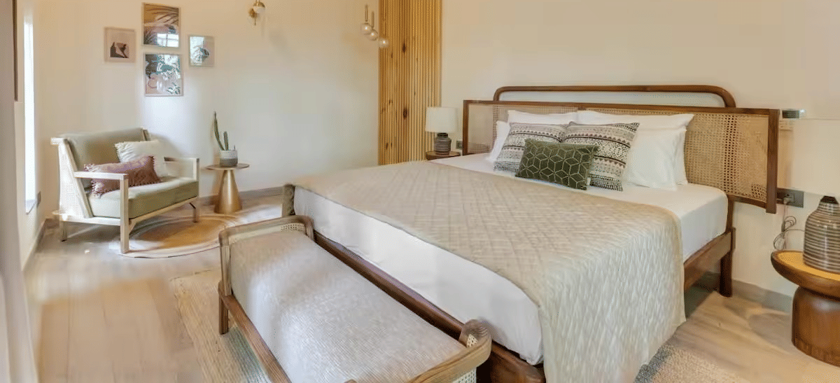 Spacious room with a neatly made bed, bedside table, seating at the foot of the bed, and a cushioned sofa at Lime Tree Villa with Private Pool | Luxury Stay in Goa.